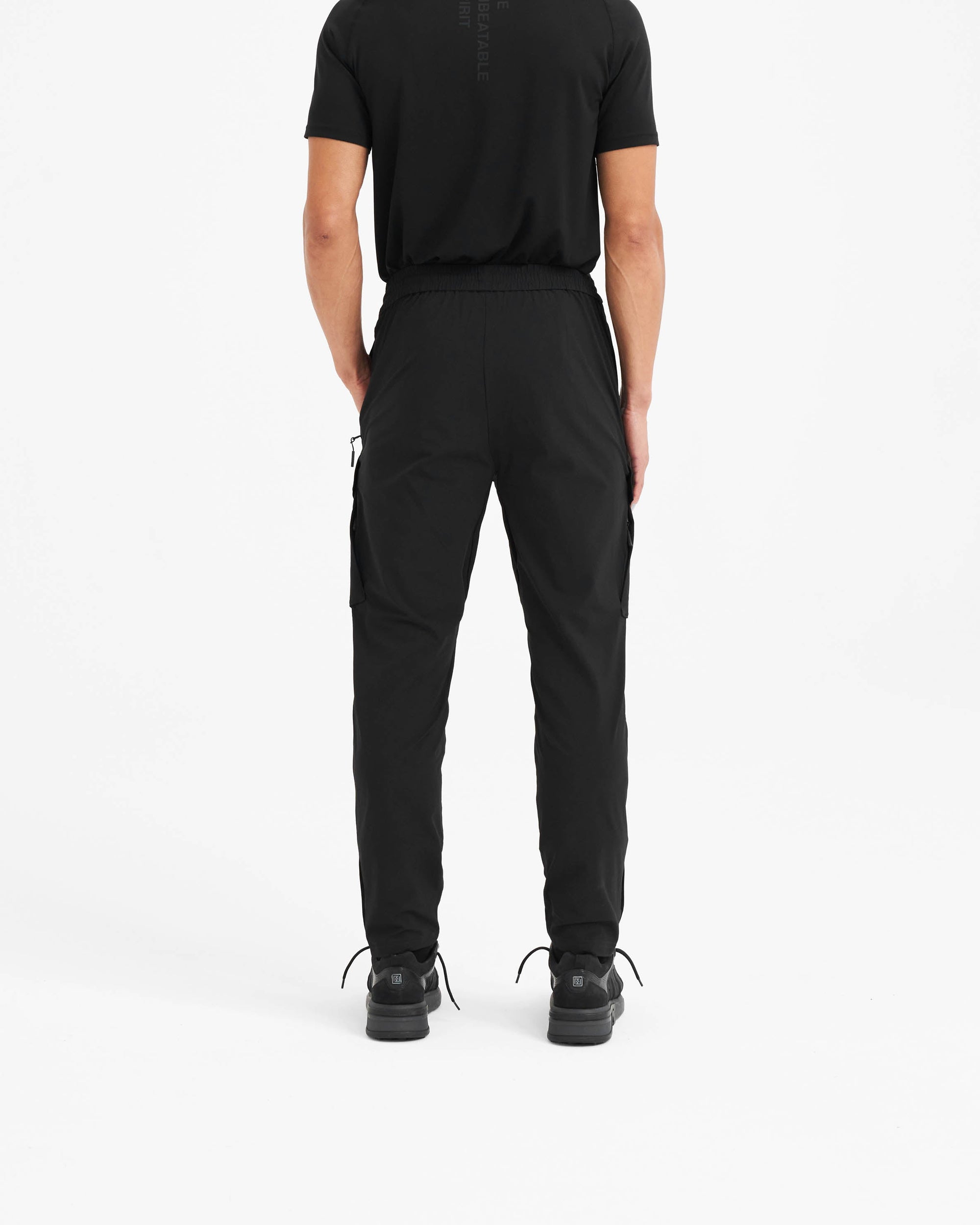 Man wearing black hiking pants on a plain white background | 247 Hiking Pant in Black | Cargo pants with adjustable belt and water-resistant finish | 247 Pants | Represent Clo