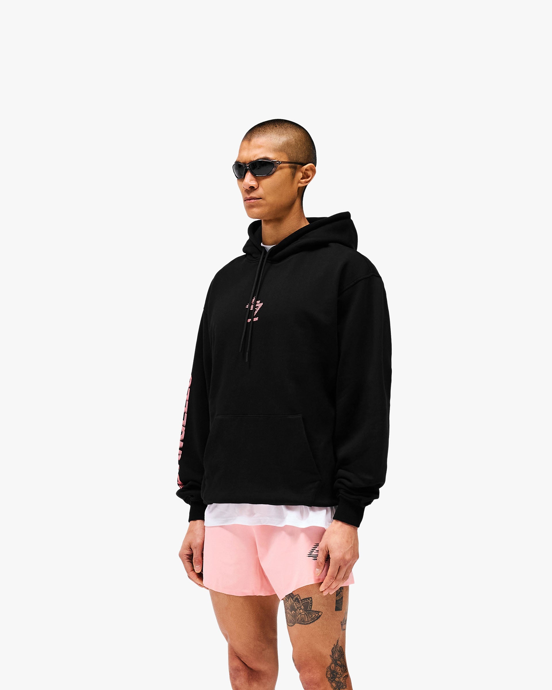 Man wearing an oversized black hoodie on a plain white background | 247 Los Angeles Hoodie in Jet Black | Oversized hoodie with 247 Los Angeles graphic | 247 Hoodies | Represent Clo