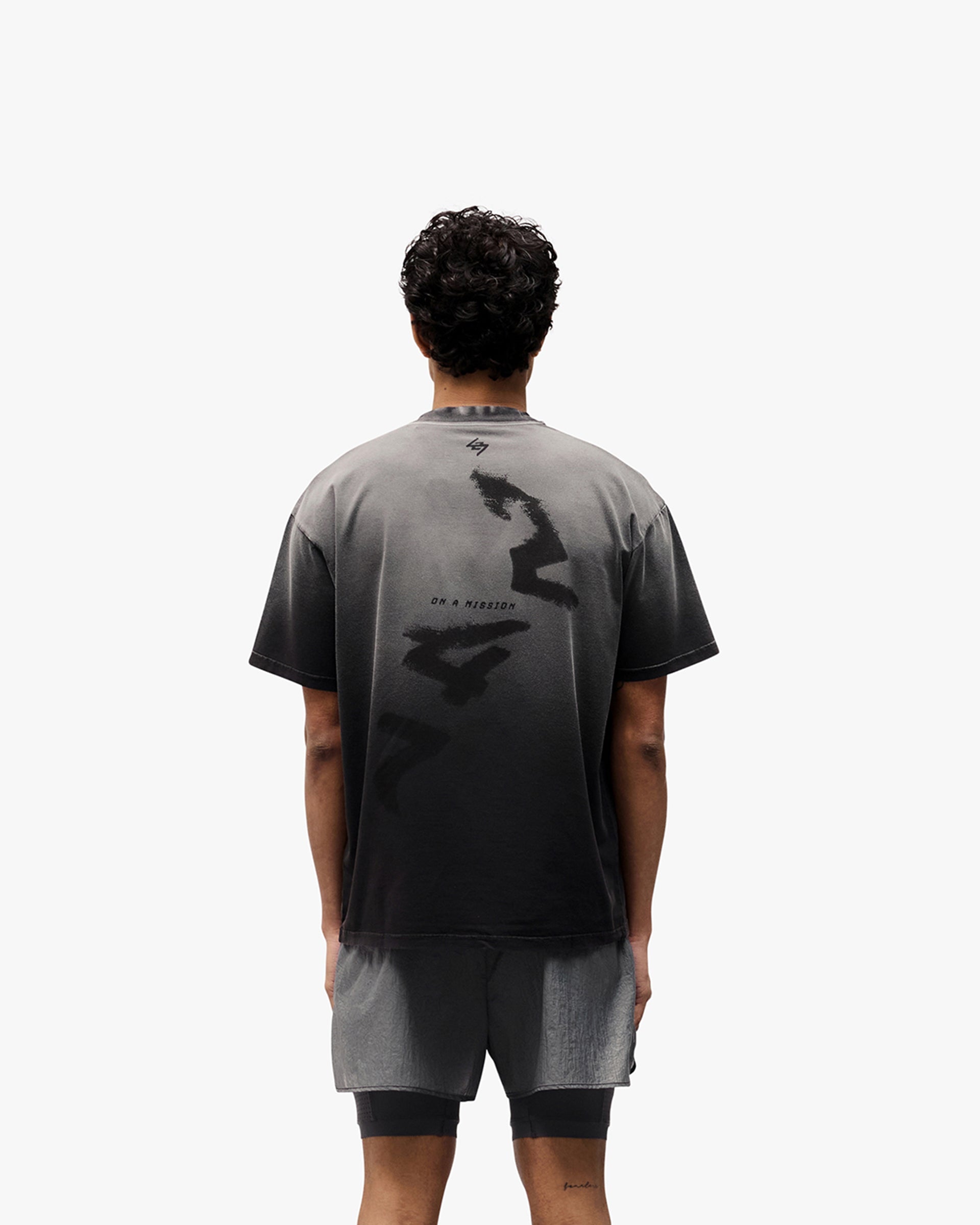 Man wearing an oversized black t-shirt with graphic print on a plain white background | 247 Motion Oversized T-Shirt in Aged Black | Oversized t-shirt with sweat-wicking fabric | 247 T-Shirts | Represent Clo