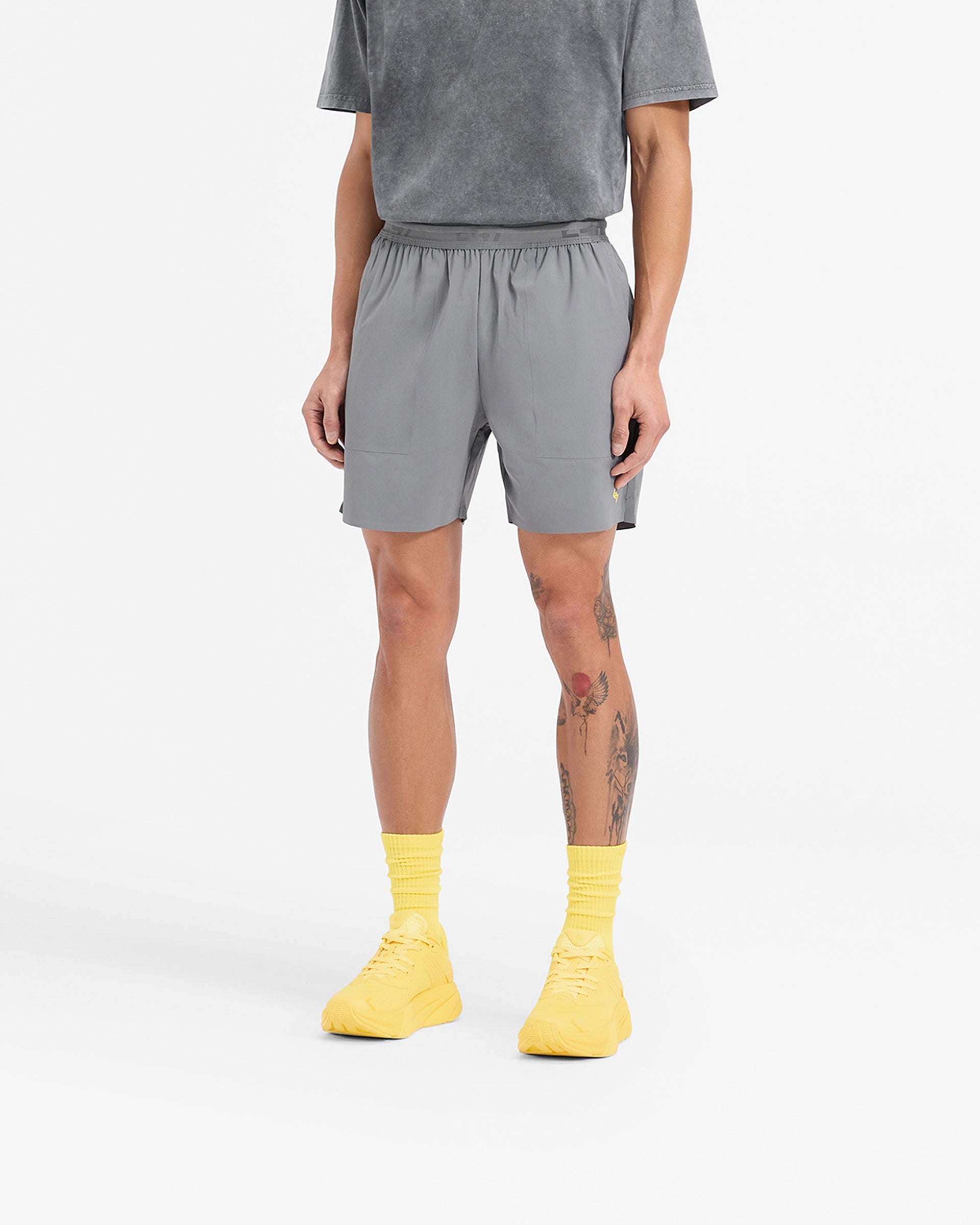 Man wearing grey shorts with yellow accents on a plain white background | Team 247 Fused Shorts in Pewter Lemon | Durable gym shorts with 4 way stretch and quick drying features | 247 Shorts | Represent Clo