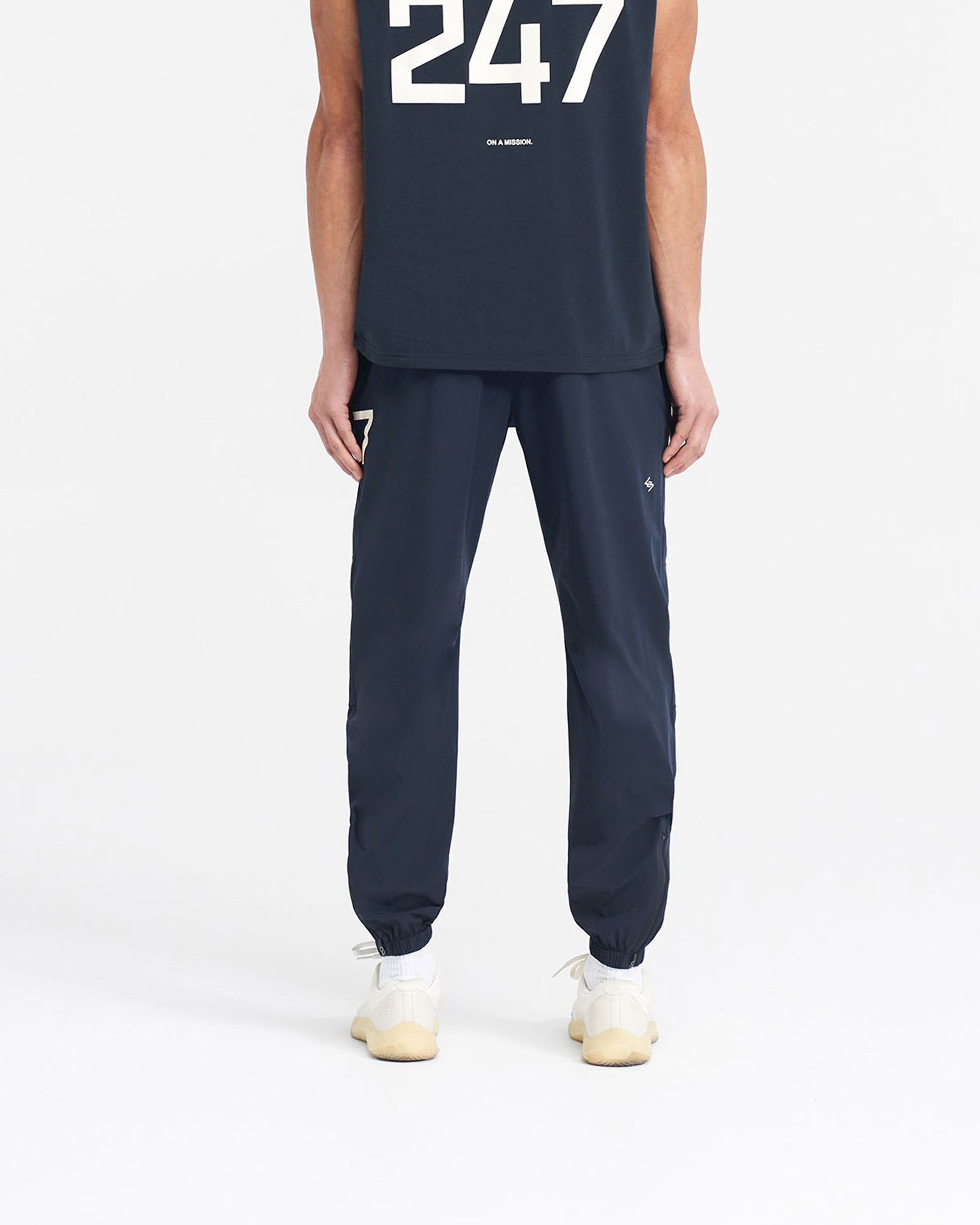 Man wearing navy training pants on a plain white background | 247 Training Pant in Navy | Nylon elastane pants with zip side and back pockets | 247 Pants | Represent Clo