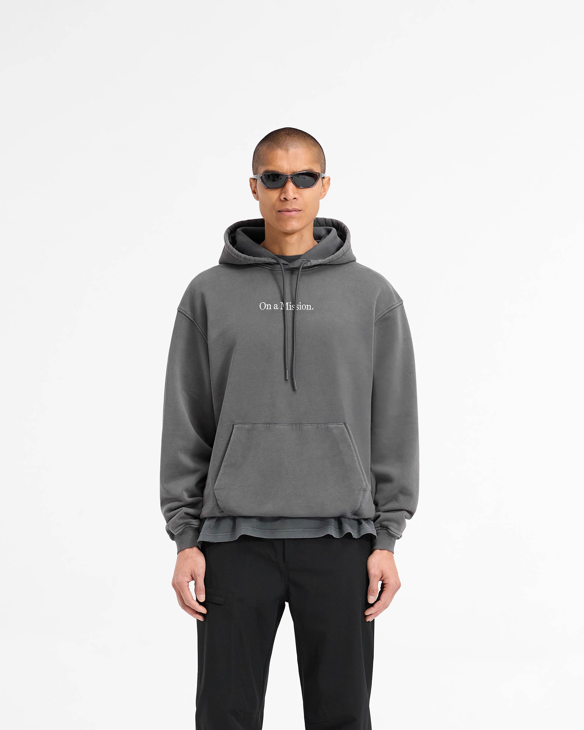 Man wearing a black hoodie on a plain white background | 247 On A Mission Hoodie in Aged Black | Slightly oversized hoodie with embroidery | 247 Hoodies | Represent Clo