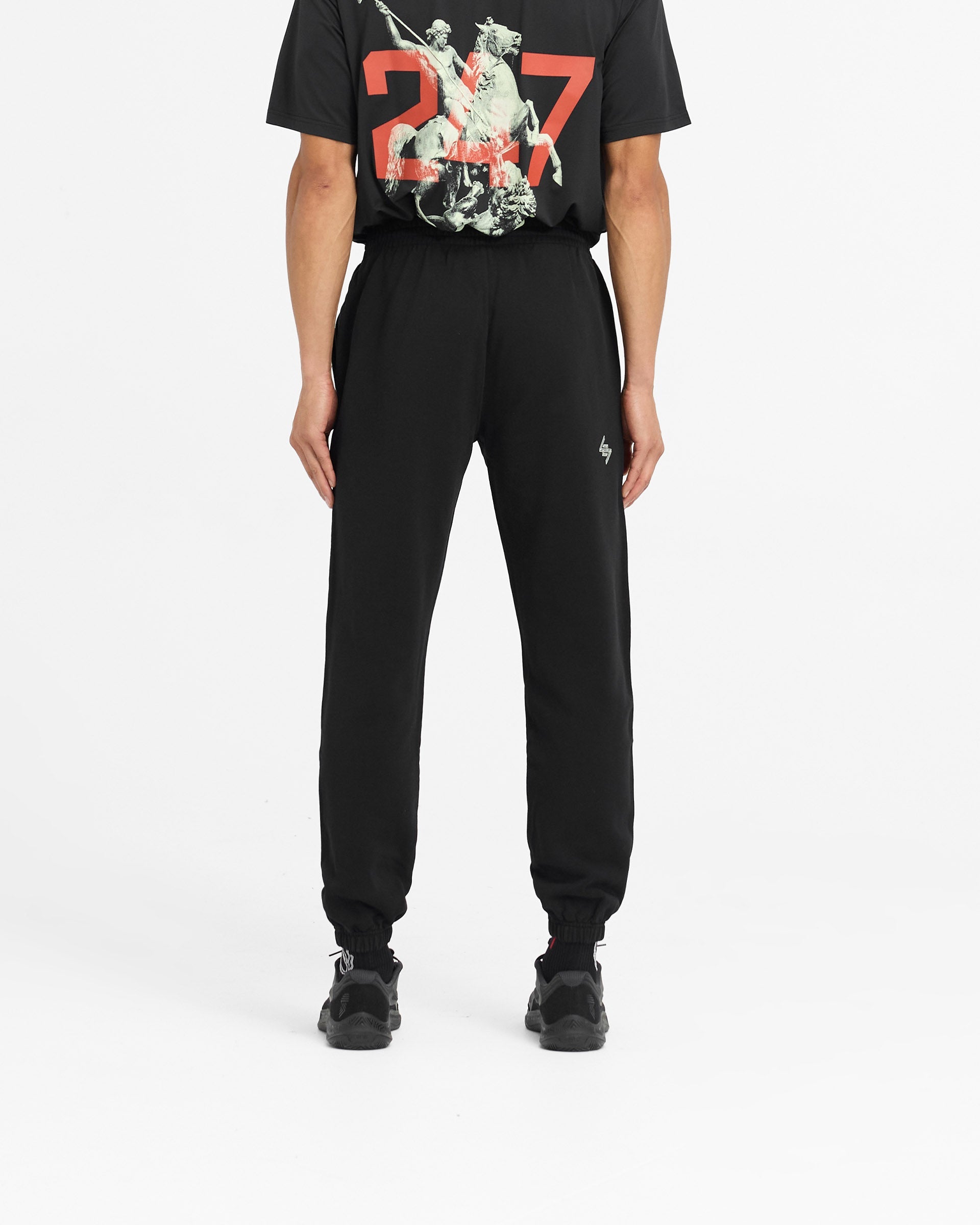 Man wearing black sweatpants on a plain white background | 247 Berlin Sweatpant in Black | Sweatpants with elasticated cuffs and zip pocket | 247 Pants | Represent Clo