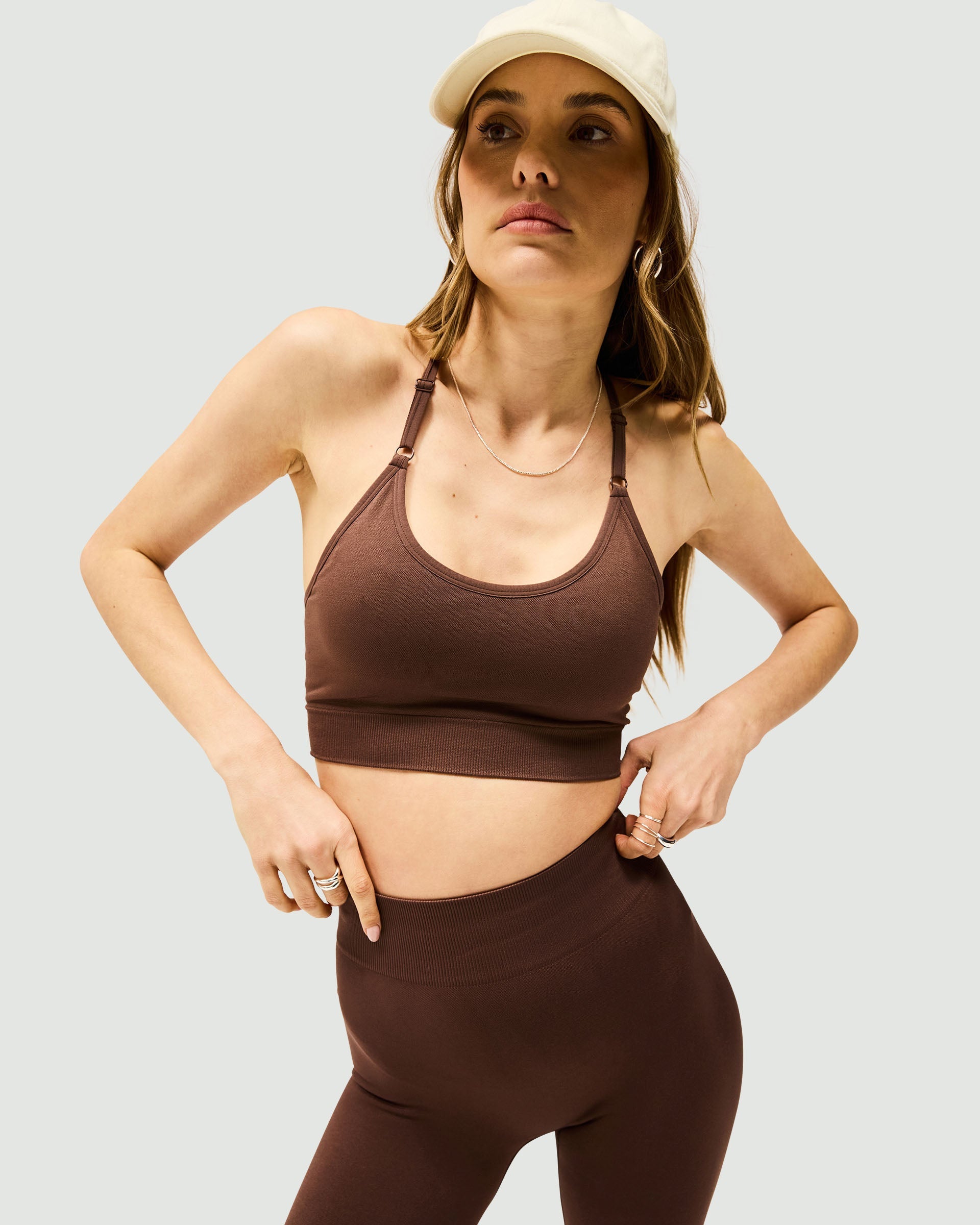 Woman wearing a mocha sports bra on a plain white background | Owners Club Seamless Low Impact Bra in Mocha | Seamless bra with T-bar back design | Womens Tops | Represent Clo