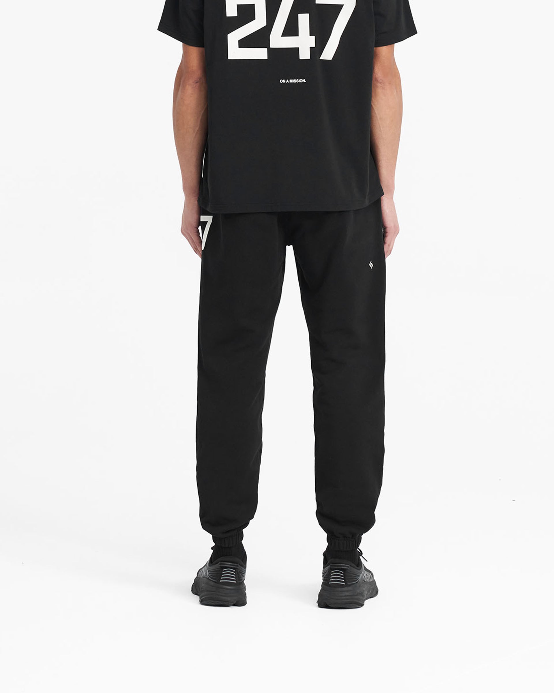 Man wearing black sweatpants on a plain white background | 247 Sweatpant in Black | Joggers with elasticated cuffs and internal drawcord | 247 Pants | Represent Clo
