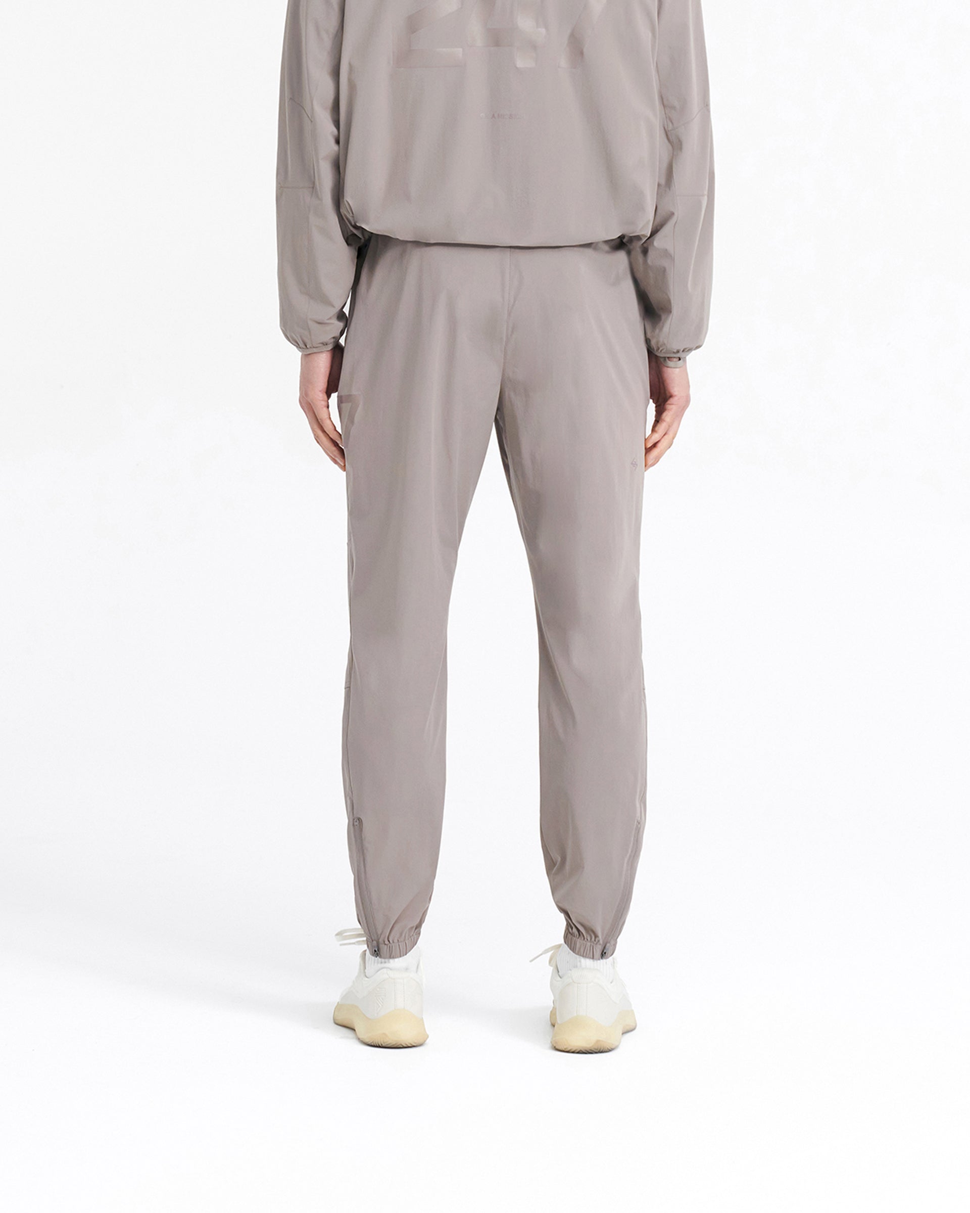 Man wearing grey training pants on a plain white background | 247 Training Pant in Cinder | Training pants with elasticated waistband and zip pockets | 247 Pants | Represent Clo