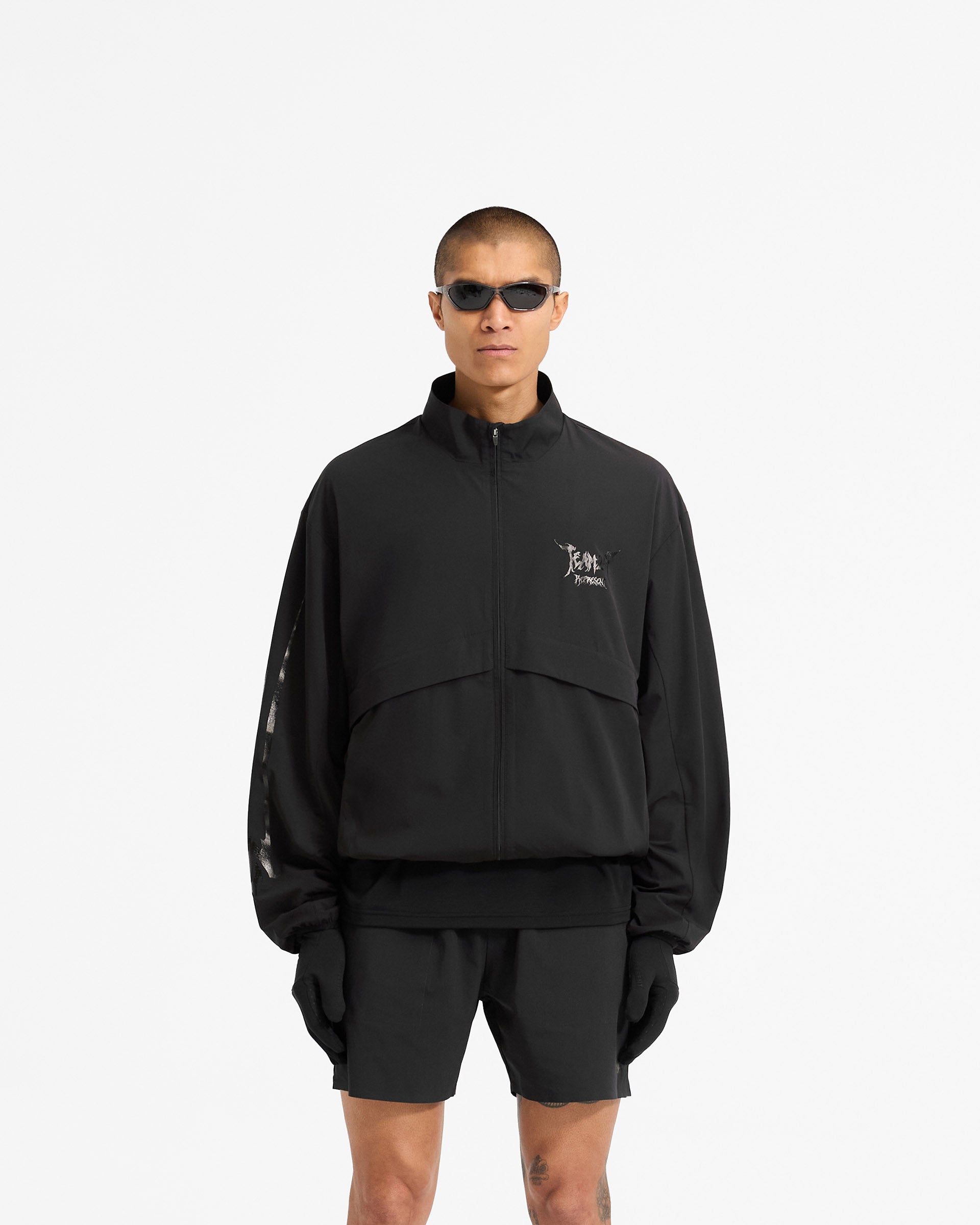 Man wearing a black track jacket on a plain white background | Team 247 X END Track Jacket in Jet Black | Track jacket with 4-way stretch shell and mesh lining | 247 Outerwear | Represent Clo