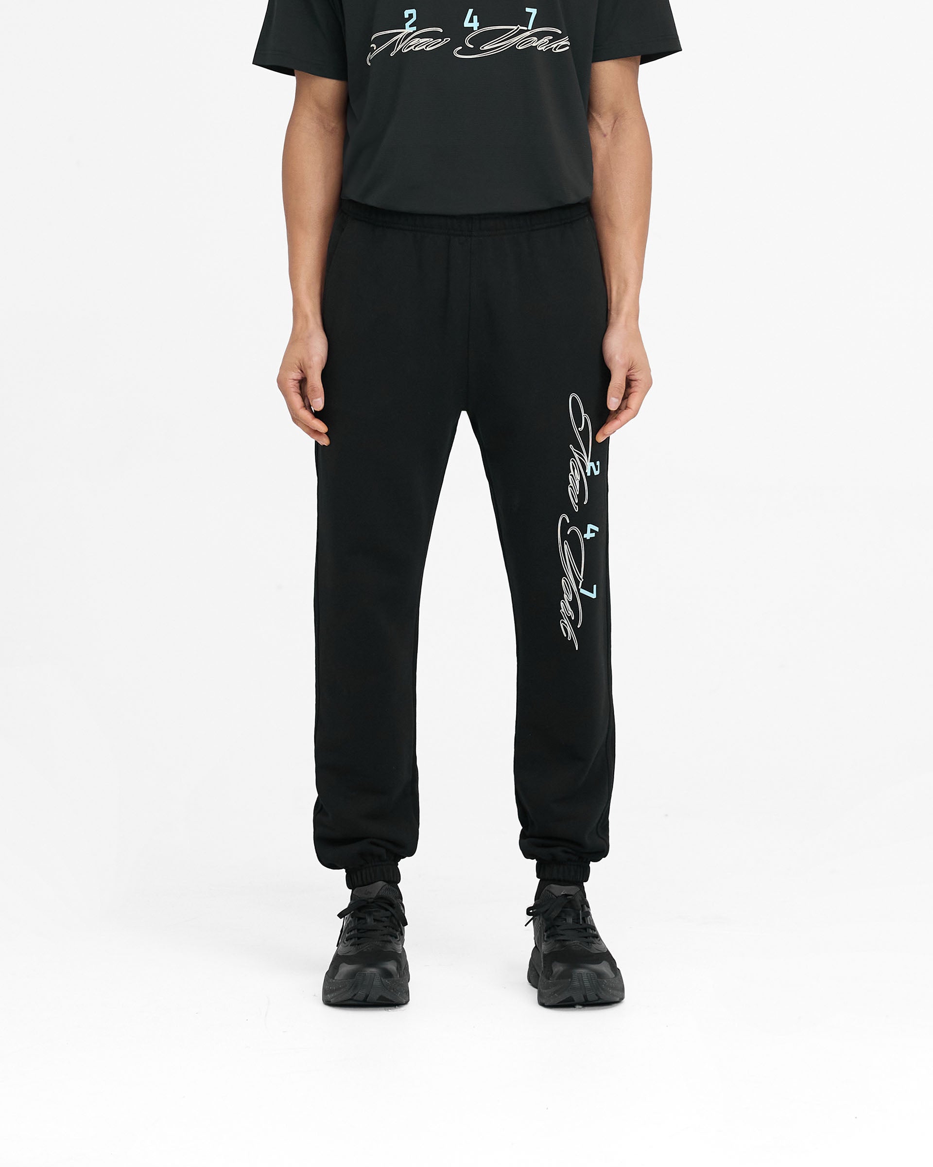 Man wearing black joggers on a plain white background | 247 New York Sweatpant in Black | Joggers with elasticated waistband and cuffs | 247 Pants | Represent Clo